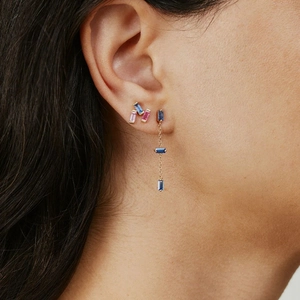 Close-up of geometric earrings with colorful rectangle gems and long chain tassels