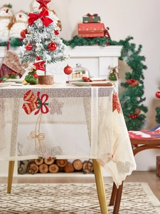 Detail of Christmas tablecloth featuring bell embroidery and hollowed-out lace on a festive table