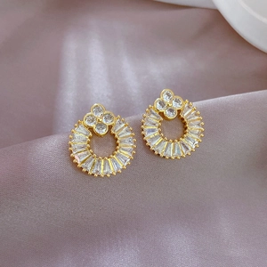 Close-up of golden four-leaf clover earrings with crystal pavé on purple silk background