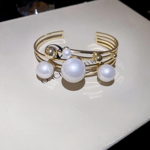 Detailed macro view of gold multi-layer hollow bracelet with pearls and beads on display