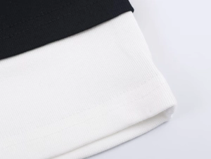 Detail of black flat-weave fabric and white ribbed trim with precise stitching