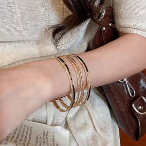 Close-up of stacked gold and black enamel bracelets worn by a model in lifestyle setting