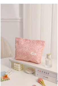 Detailed view of pink leopard print cosmetic bag with brand label on a storage shelf