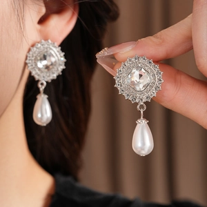 Close-up of elegant silver drop pearl earrings with square diamond settings on model