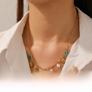 Detail of gold seashell necklace with pearls and blue beads on a female model