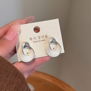 Detailed close-up of white enamel twisted silver earrings on brand display card