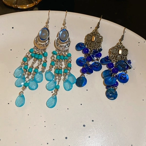 Detail of vintage bohemian shell earrings with turquoise beads and metallic tassels