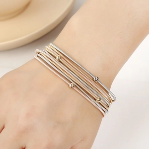 Detail of multi-layered metallic spring bracelets in silver, gold, and rose gold with beads