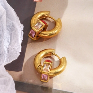 Détail macro de créoles géométriques plaquées or 18 carats avec zircons rouges et roses