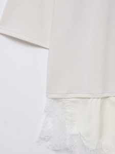 Detailaufnahme eines cremefarbenen T-Shirts mit zartem weißem Spitzenbesatz am Saum