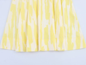 Detailed view of yellow abstract vertical stripes and hem stitching on casual midi skirt