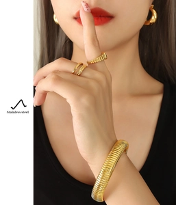 Detail shot of gold-plated stainless steel jewelry set including spiral bangle and rings