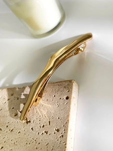 Detailed close-up of a lava style golden wave hair clip on a natural stone base