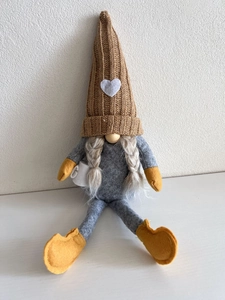 Detail of knitted gnome plush with heart hat holding a white coffee cup ornament