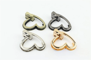 Dettaglio di serrature a rotazione a forma di cuore per borse in oro argento bronzo e nero