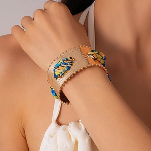 Macro detail of gold metal cuff bracelet with blue floral silk fabric inlay