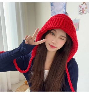 Détail du bonnet en grosse maille rouge avec protège-oreilles et tresses pour femme