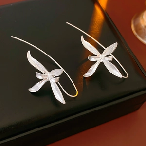 Macro shot of silver iris flower earrings on a black reflective jewelry box surface