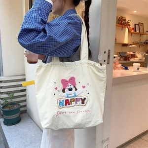 Close-up of a cream tote bag featuring cute dog embroidery and a colorful Happy slogan