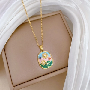 Macro detail of gold oval necklace with colorful enamel floral inlay on a soft background