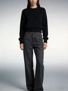 Detail of high waist straight leg denim trousers paired with a black knit sweater