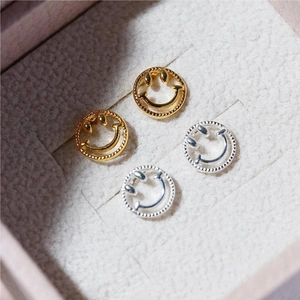 Smiling face stud earrings in gold and silver finish on grey velvet jewelry box