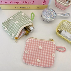 Detailed view of floral lace embroidery on green and pink checkered canvas coin purses