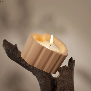 Detailopname van beige keramische kaars met strepen op rustieke houten ondergrond