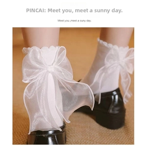 Detail of white mid-calf socks featuring a large sheer organza bow in Lolita style