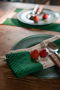 Detailed close-up of handmade green and beige woven cotton placemat with tassel fringe