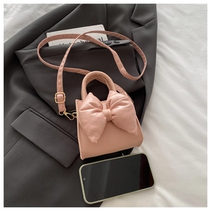 Close-up of pink mini PU leather handbag with a large bow detail and a top handle