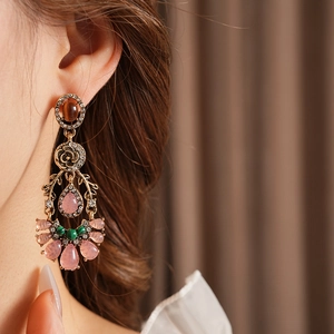 Detail of vintage gold-tone earrings with pink and green crystals on a female model