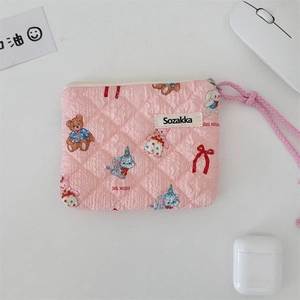 Detailed view of pink quilted makeup bag with cute cartoon bear and rabbit patterns