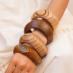 Detail view of four vintage wooden bangles with unique grain patterns and rivets