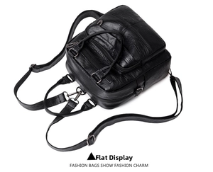Detail view of black faux leather backpack with multiple zipper pockets and metallic hardware