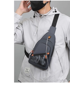 Detail of dark grey men's chest bag featuring camo pocket and vibrant orange zipper accents