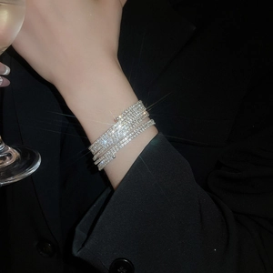 Dettaglio macro di un bracciale elastico a più fili con cristalli su un polsino nero