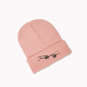 Gros plan du bonnet en tricot rose avec broderie noire minimaliste de deux mains touchant