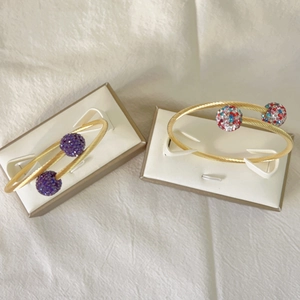 Détail de bracelets torsadés plaqués or 18k avec sphères pavées de cristaux colorés