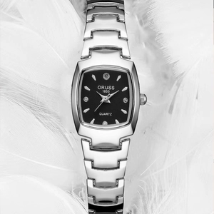 Detailed macro of silver quartz watch with black rectangular dial on white feathers