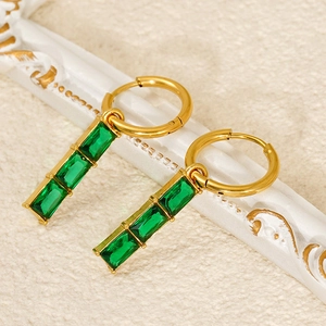 Macro shot of gold bamboo joint earrings with three green rectangular gemstones