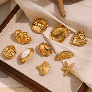 Macro shot of 9-piece gold-plated jewelry set featuring sea shells and heart brooch designs