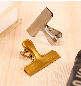 Close-up of gold and silver stainless steel sealing clips on a light wood background