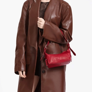 Minimalist red leather crescent underarm bag with adjustable strap on leather coat