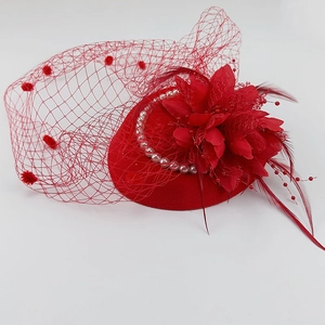 Macro detail of red felt fascinator with mesh veil, feathers and pearl accents