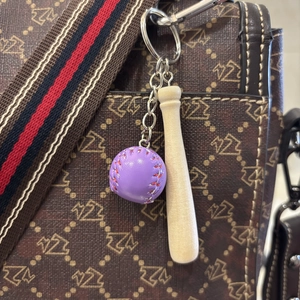Miniature baseball bat and purple ball keychain hanging as an ornament on a bag detail