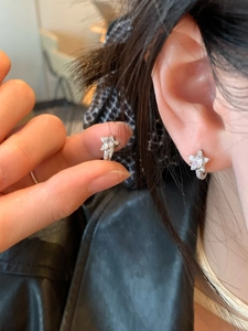 Gros plan de boucles d'oreilles étoiles en argent avec zircons brillants sur l'oreille