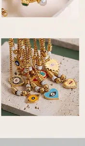 Detail showing various 18K gold plated evil eye charms in heart and sun shapes with colorful enamel