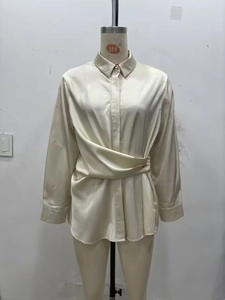 Détail du chemisier en satin avec devant croisé plissé et fermeture par bouton doré