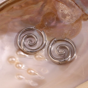 Makroaufnahme silberner Spiral-Ohrringe auf einem dekorativen Perlmutt-Hintergrund